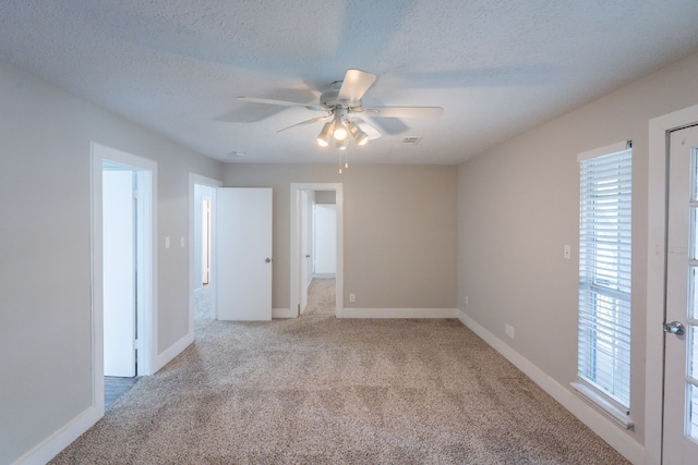 unfurnished room with visible vents, a ceiling fan, carpet flooring, and a wealth of natural light