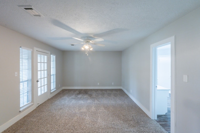 unfurnished room featuring carpet floors, visible vents, baseboards, ceiling fan, and a textured ceiling