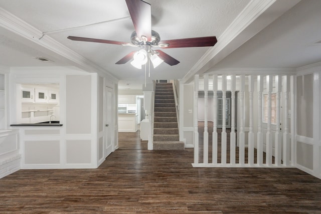 interior space featuring crown molding, ceiling fan, stairs, dark wood-type flooring, and visible vents