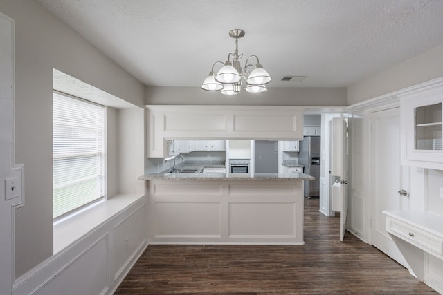 kitchen featuring an inviting chandelier, a sink, appliances with stainless steel finishes, and white cabinets