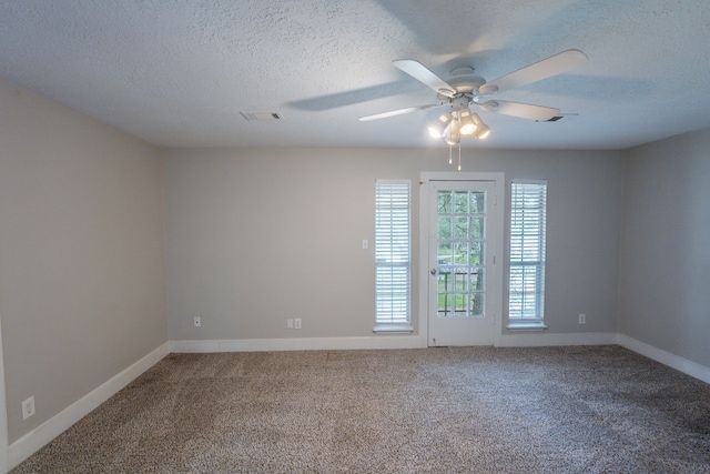 empty room with a ceiling fan, carpet flooring, a textured ceiling, and visible vents