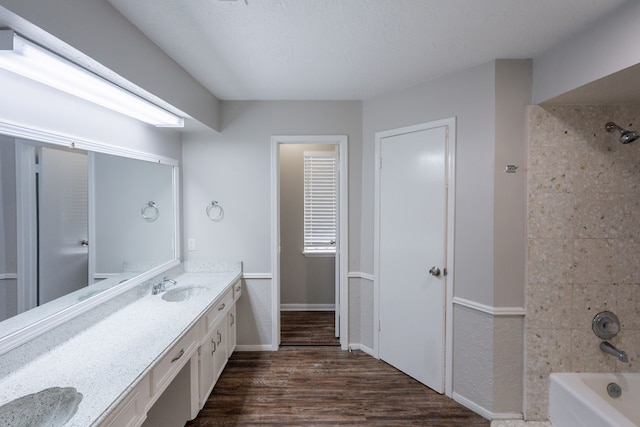 bathroom with vanity, baseboards, wood finished floors, and bathtub / shower combination