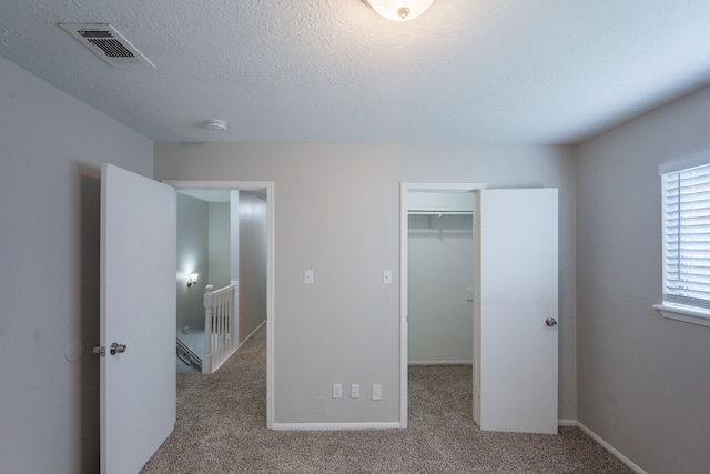 unfurnished bedroom featuring visible vents, a closet, baseboards, a walk in closet, and carpet