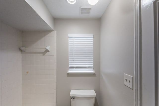 bathroom featuring toilet, visible vents, and a tile shower