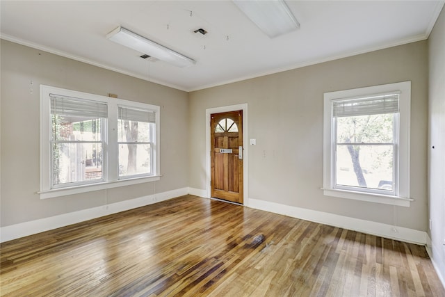 foyer entrance featuring crown molding, baseboards, wood finished floors, and visible vents