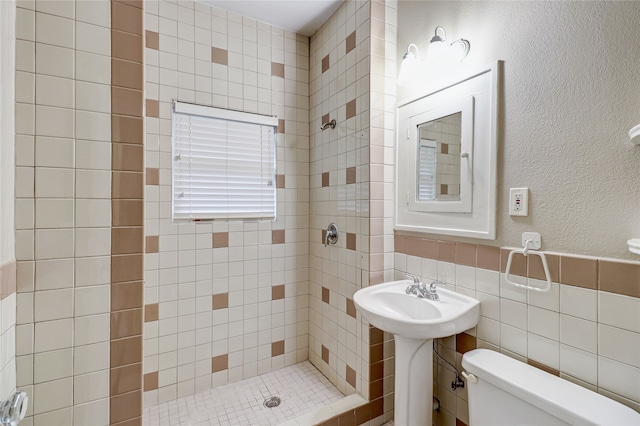 bathroom featuring wainscoting, tile walls, a stall shower, and toilet