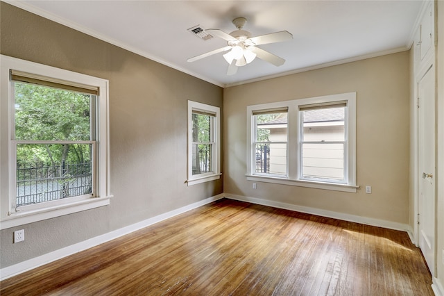 unfurnished room with wood-type flooring, ornamental molding, baseboards, and a healthy amount of sunlight