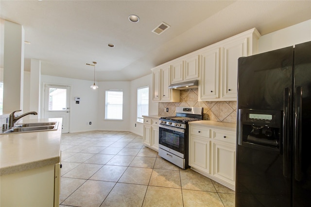 kitchen with a sink, stainless steel range with gas cooktop, under cabinet range hood, visible vents, and black fridge with ice dispenser