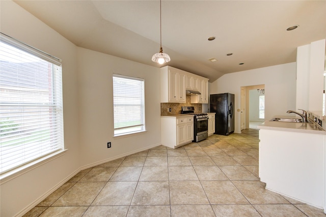 kitchen with decorative backsplash, stainless steel range with gas stovetop, a sink, light tile patterned floors, and freestanding refrigerator