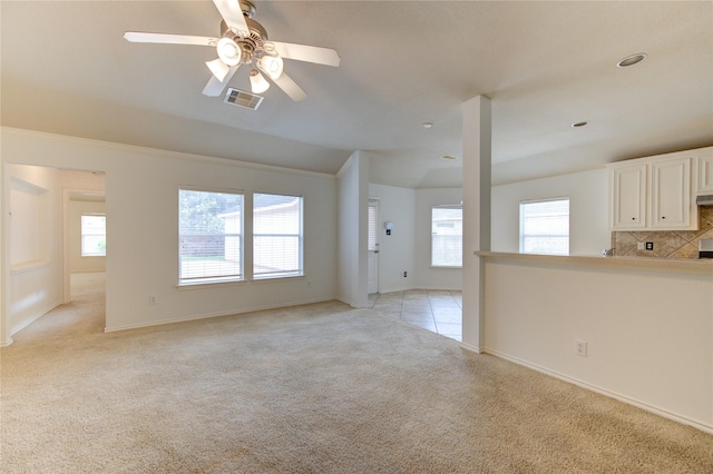 unfurnished living room with ceiling fan, visible vents, light carpet, and baseboards