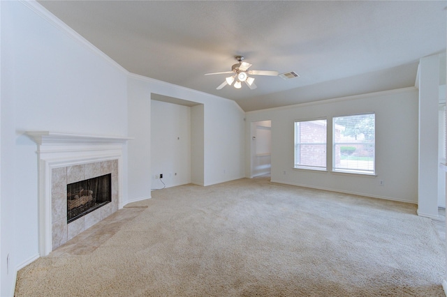 unfurnished living room with a ceiling fan, visible vents, a tiled fireplace, carpet floors, and ornamental molding
