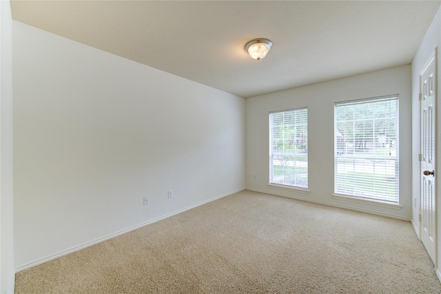 unfurnished room featuring baseboards and light colored carpet