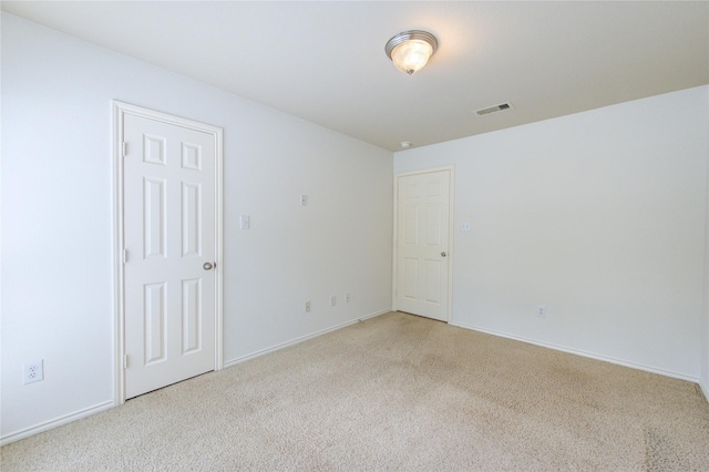 empty room featuring baseboards, light colored carpet, and visible vents