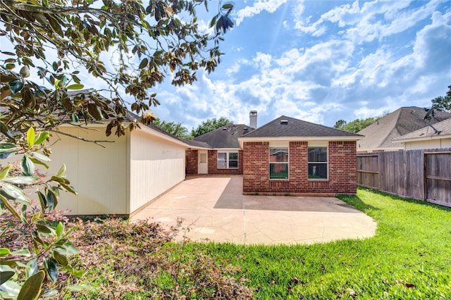 back of property with brick siding, a lawn, fence, and a patio