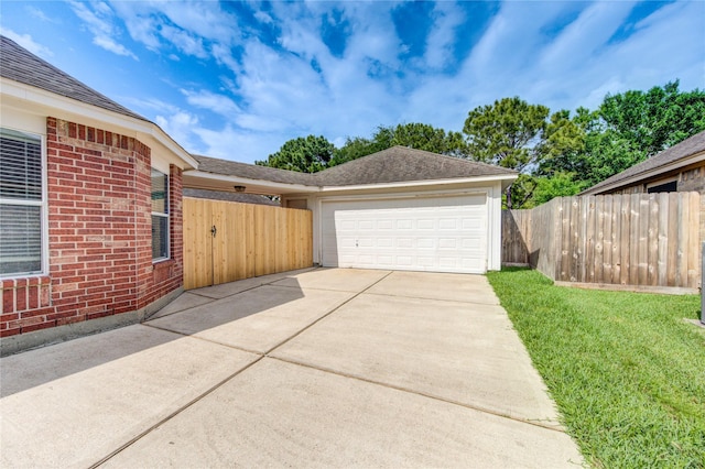 view of home's exterior with an attached garage, fence, driveway, and brick siding