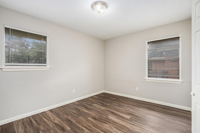 unfurnished room with dark wood-style flooring and baseboards