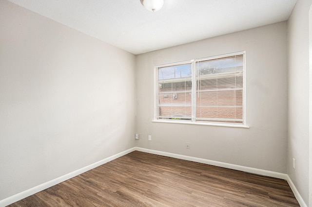 spare room featuring baseboards and wood finished floors