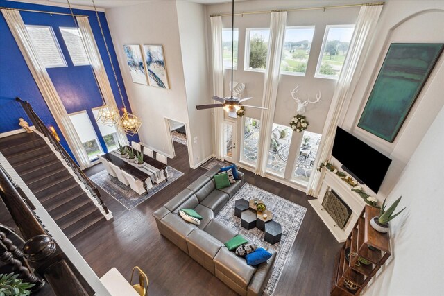 living area with baseboards, ceiling fan with notable chandelier, stairs, and wood finished floors