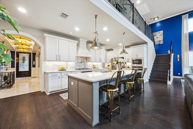 kitchen with visible vents, arched walkways, built in microwave, light countertops, and custom exhaust hood