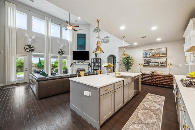 kitchen featuring light countertops, arched walkways, open floor plan, and gray cabinets