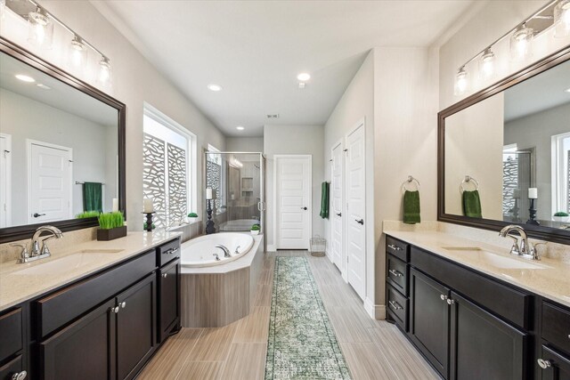 full bath with a sink, a stall shower, a garden tub, and two vanities