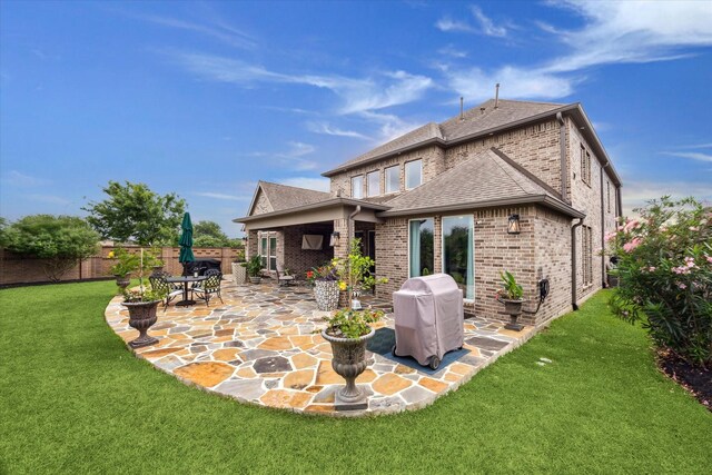 back of property featuring brick siding, fence, a patio, and roof with shingles