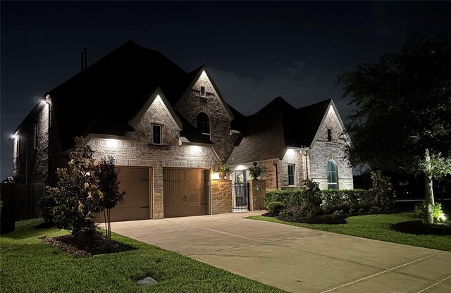 french country inspired facade with a yard, brick siding, fence, concrete driveway, and stone siding