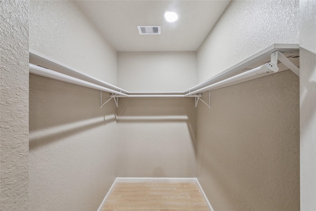 walk in closet with visible vents and wood finished floors