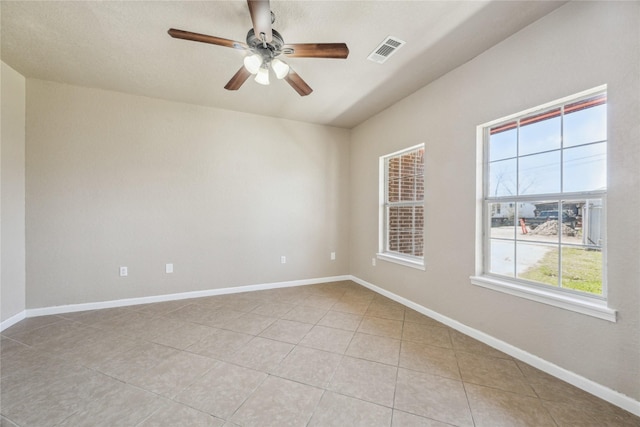 spare room with baseboards, ceiling fan, light tile patterned flooring, and visible vents