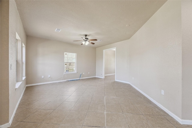 spare room with a textured ceiling, a ceiling fan, light tile patterned flooring, and visible vents