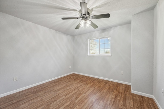 spare room with baseboards, ceiling fan, and wood finished floors