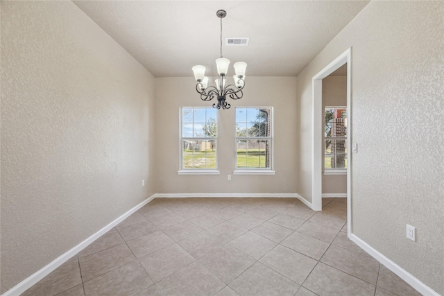 empty room featuring a notable chandelier, a textured wall, visible vents, and light tile patterned flooring