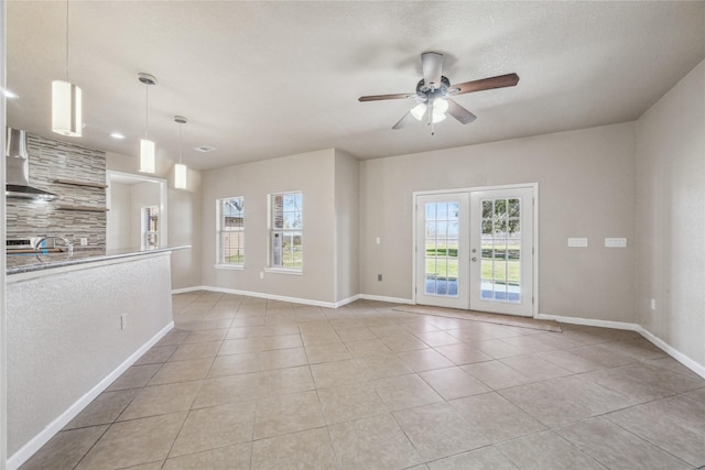 unfurnished living room with baseboards, ceiling fan, light tile patterned floors, and french doors
