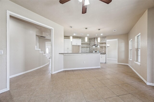 unfurnished living room featuring baseboards, a ceiling fan, and light tile patterned floors