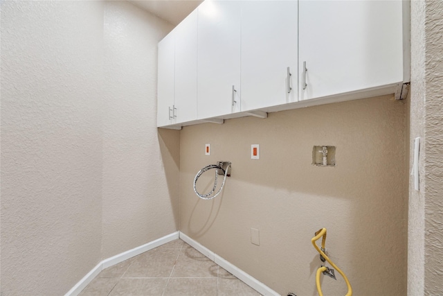 laundry area featuring washer hookup, baseboards, light tile patterned flooring, and cabinet space