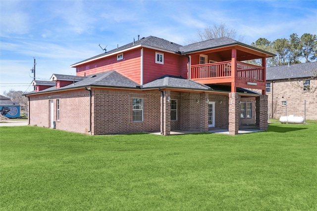 rear view of house featuring a yard, brick siding, a balcony, and a patio area