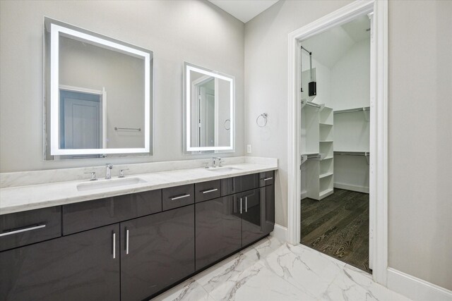 full bath featuring double vanity, a walk in closet, a sink, and marble finish floor