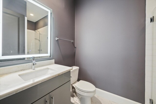 bathroom featuring toilet, baseboards, a shower, and vanity