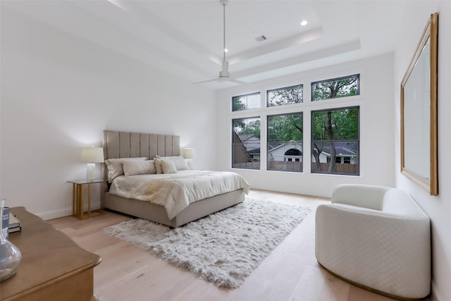 bedroom featuring recessed lighting, a raised ceiling, baseboards, and light wood-type flooring