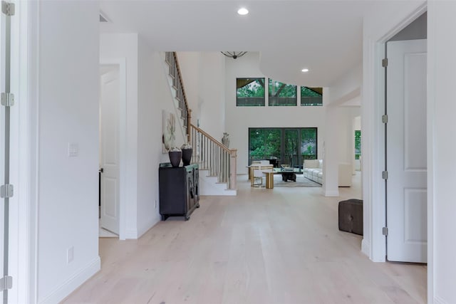 foyer featuring a high ceiling, light wood-style floors, recessed lighting, baseboards, and stairway