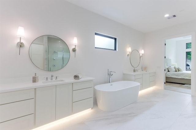 ensuite bathroom featuring a freestanding bath, a sink, marble finish floor, two vanities, and visible vents