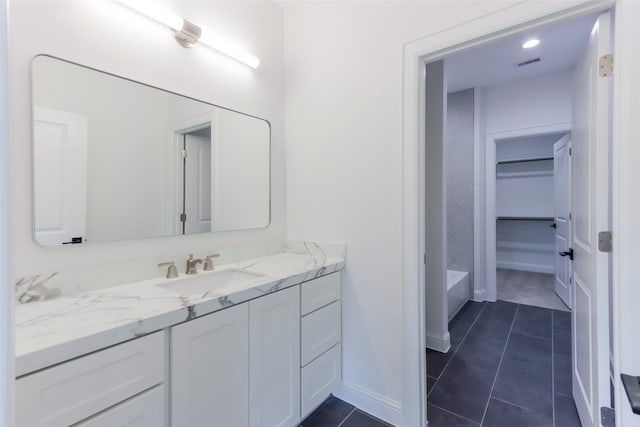 bathroom featuring a tub, visible vents, tile patterned flooring, vanity, and baseboards