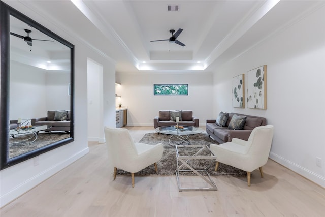 living room with visible vents, ornamental molding, wood finished floors, ceiling fan, and a raised ceiling