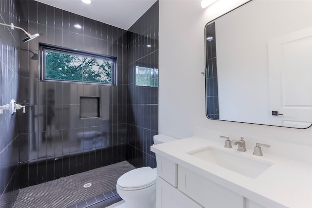 full bath featuring vanity, a tile shower, and toilet