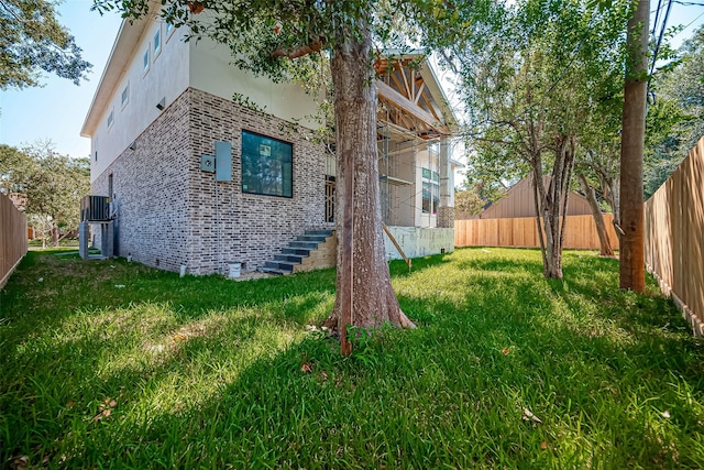 view of side of property featuring brick siding, a fenced backyard, a lawn, and stucco siding