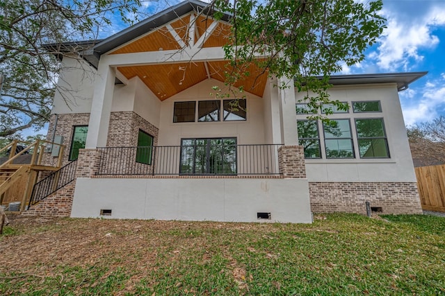 back of property featuring crawl space, brick siding, a yard, stairs, and stucco siding