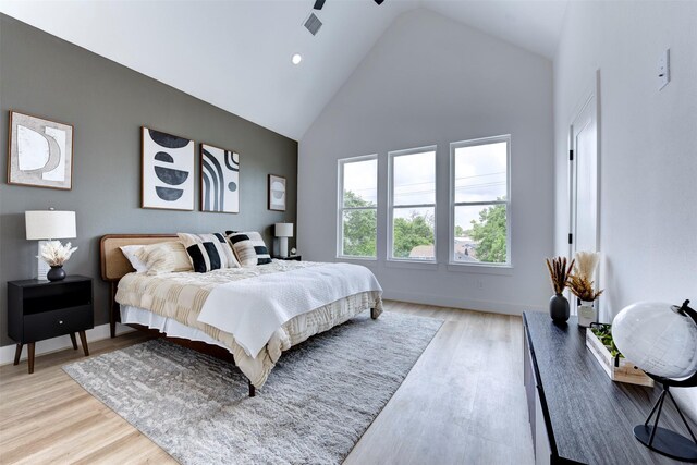 bedroom featuring light wood-type flooring and high vaulted ceiling