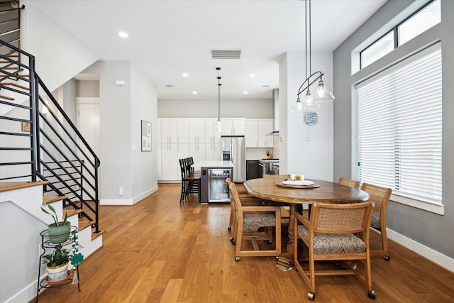 dining room with wine cooler, baseboards, light wood-style flooring, and visible vents