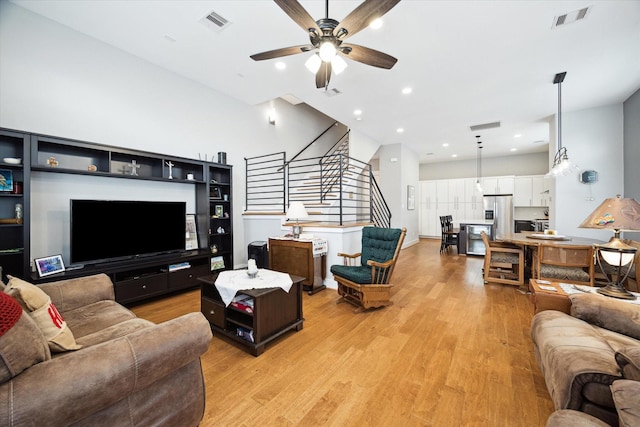 living room featuring a ceiling fan, visible vents, and light wood-type flooring