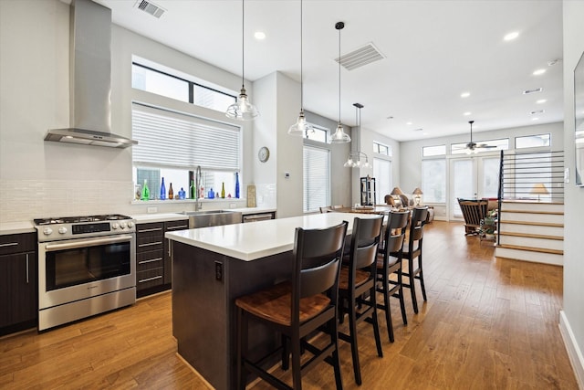 kitchen featuring a sink, visible vents, wall chimney exhaust hood, and gas range
